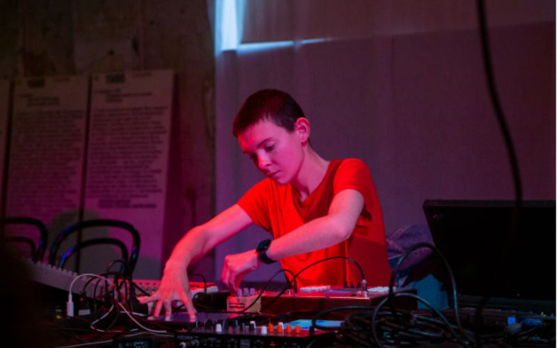A person in a red T-shirt operates a turntable.